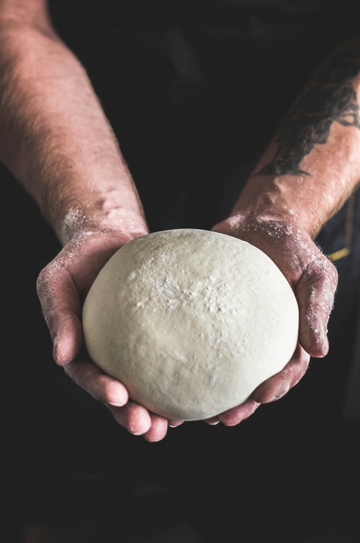 Un pâton de pâte à pizza dans les mains du pizzaiolo