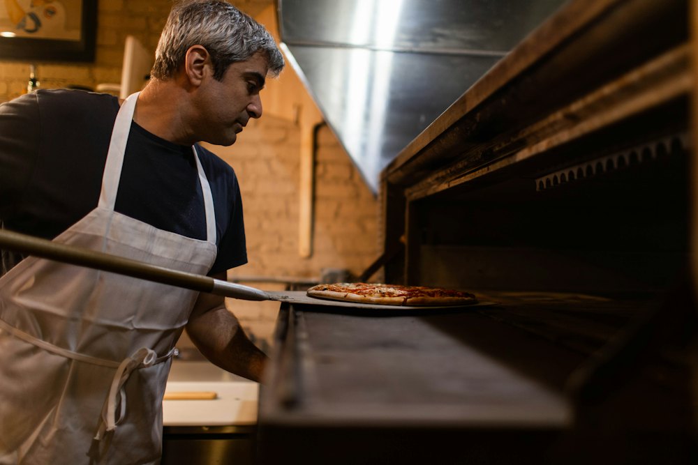 Le pizzaiolo enfourne une pizza
